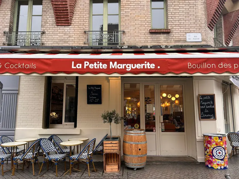 La Petite Marguerite French restaurant storefront with red awning, outdoor patio seating, and charming brick building facade