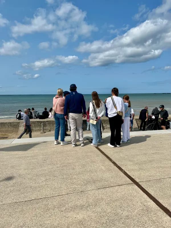 Visitors enjoying scenic ocean views from a seaside promenade on a sunny day with blue skies and calm waters.