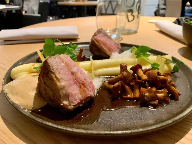 Seared duck breast with creamy mashed potatoes, sautéed wild mushrooms, and micro greens on a rustic ceramic plate.